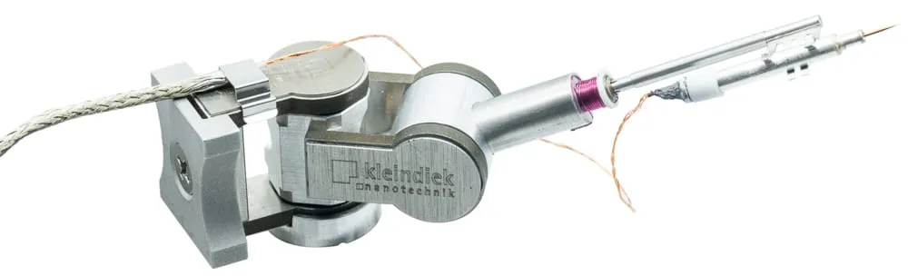 The MSU micro-soldering plug-in on a Kleindiek MM3A-EM micromanipulator, its heated tip wound with fine copper heating wire.