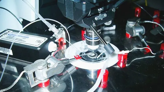 A full recording bench with two MM3A-LS units mounted either side of a 60x objective, cables and red terminal caps visible.