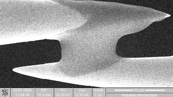SEM close-up of a cured SemGlu bond joining two fibres, with a 10 micrometre scale bar.