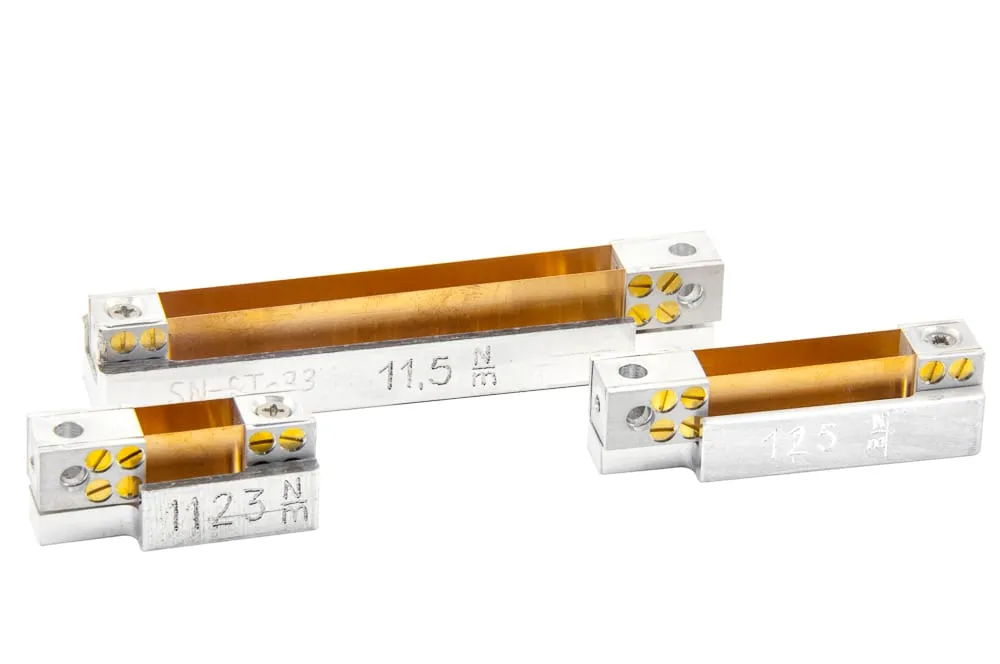 Three SpringTable force-measurement devices of different sizes, each machined in aluminium with a copper spring strip engraved with its spring constant (for example 11.5 N/m and 125 N/m).