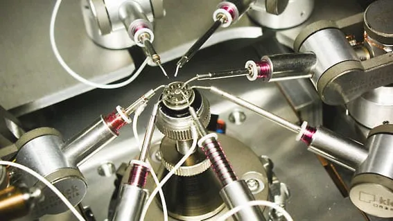 Several MM3A-EM probe tips converging on a mounted sample stub from multiple angles.